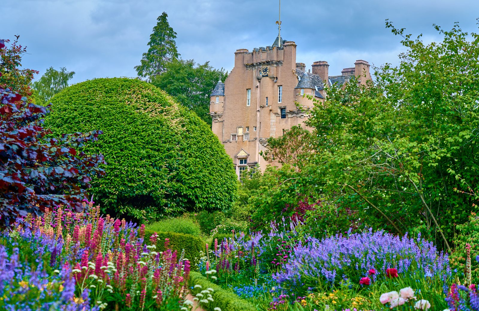 Crathes Castle tower house seen from the historic walled gardens with manicured hedges in the foreground